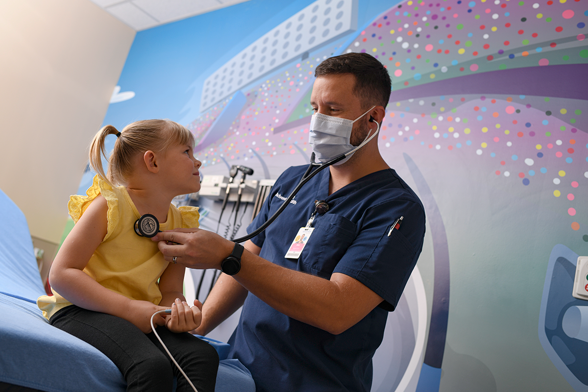 AdventHealth A healthcare worker performing a medical examination on a child using a stethoscope.